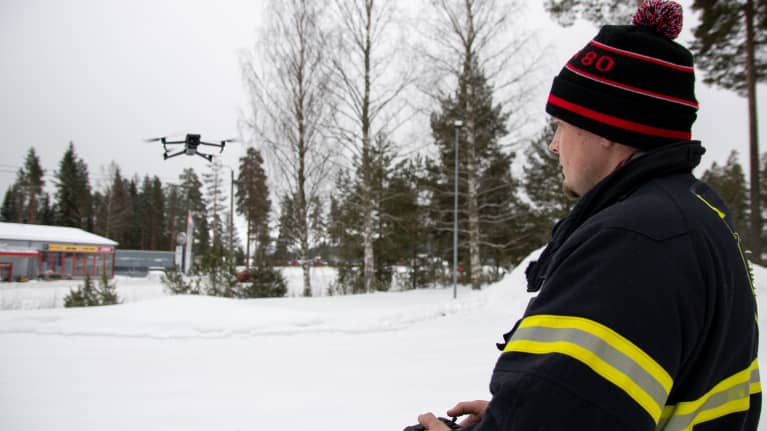 VPK:n asuun pukeutunut Heikki Isomäki lennättämässä pelastuslaitoksen droonia.