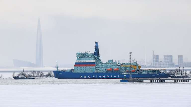 A Russian nuclear icebreaker on ice with buildings in the background.