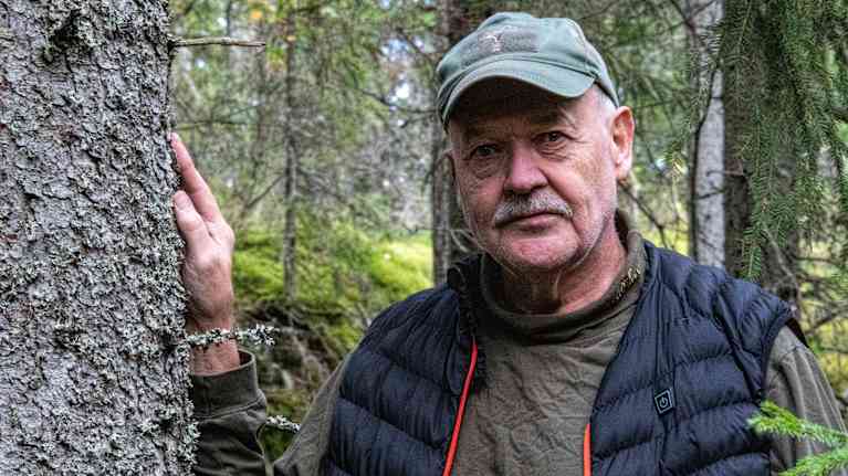 En man står invid ett träd.