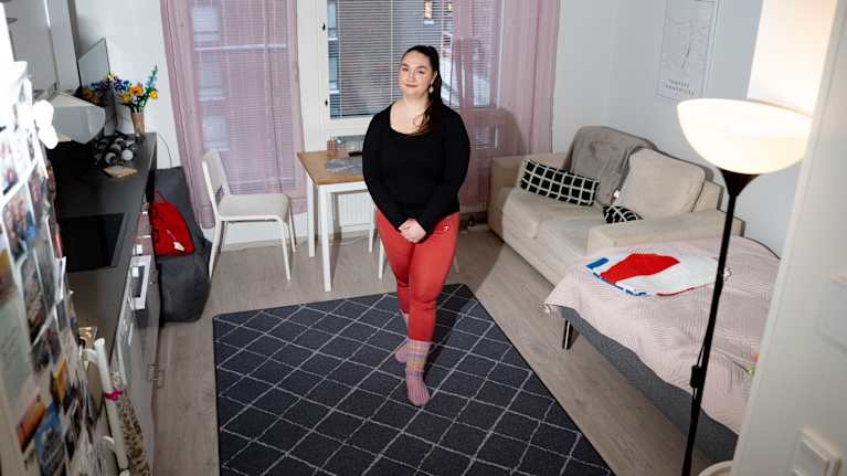 Nainen seisoo yksiönsä keskellä.