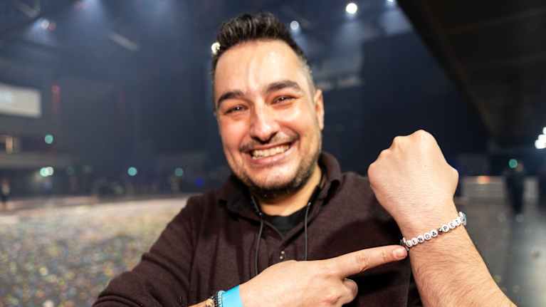 Mies katsoo kameraan ja osoittaa rannekoruaan.