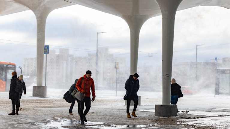 Ihmisiä kävelee Helsingin Pasilassa lumisateessa ja tuulessa.