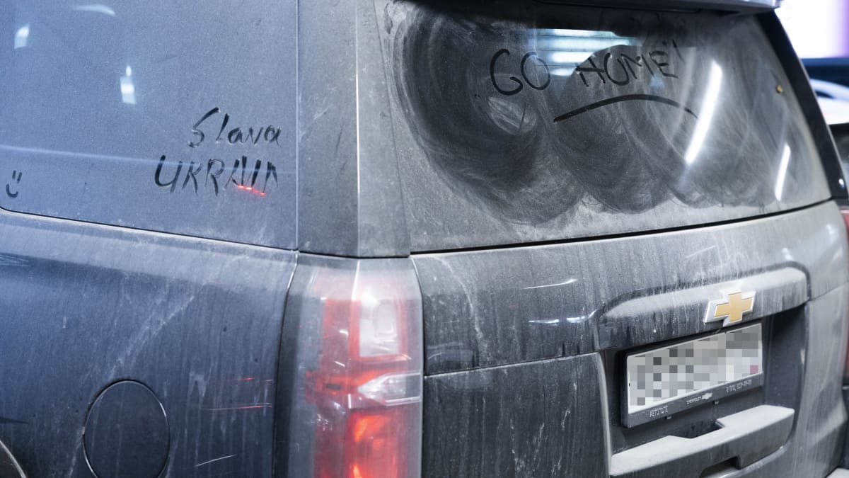 Rear view of a Chevrolet SUV with the words "slava Ukraini" and "go home" written in dust on its windows. 