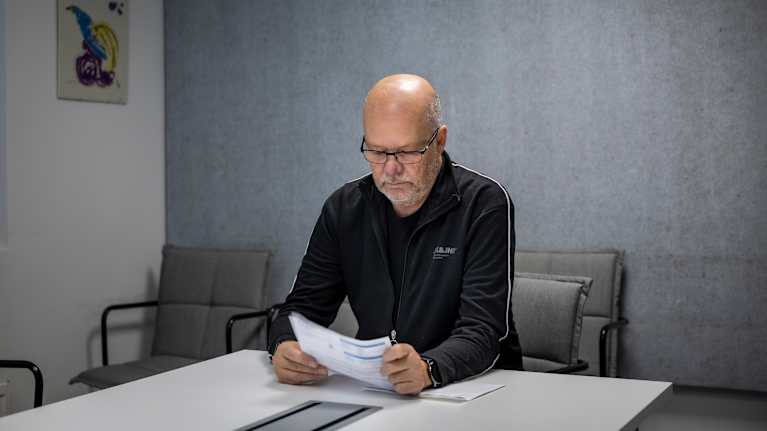 Hannu Lahti istuu pöydän ääressä ja pitää laskua kädessään.