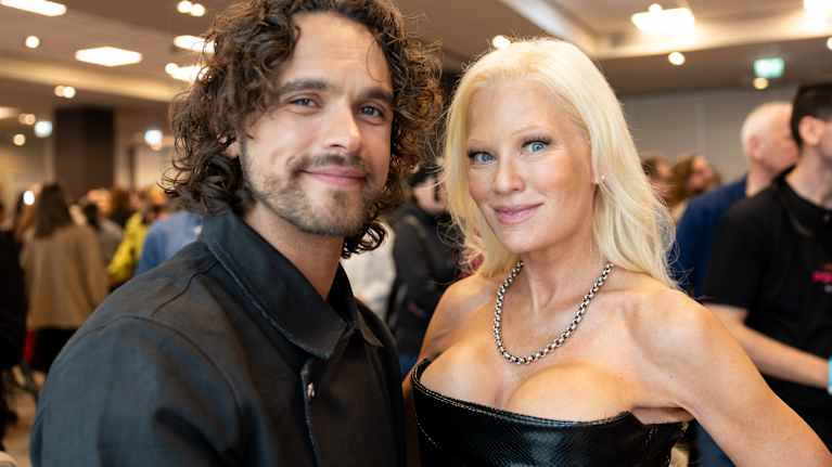 Tummahiuksinen mies ja vaaleatukkainen nainen poseeraavat kameralle.