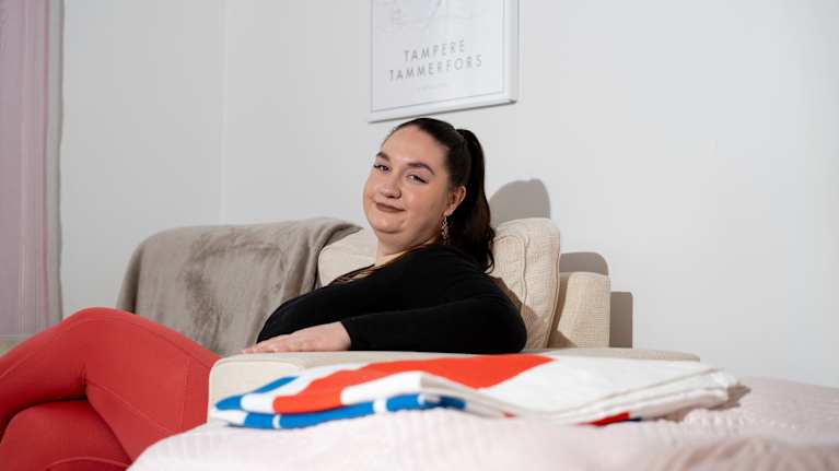 Nainen istuu sohvalla kotonaan.