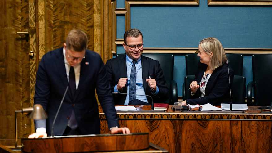 Antti Lindtman puhuu, Petteri Orpo ja Riikka Purra kuuntelevat ministeriaitiossa.
