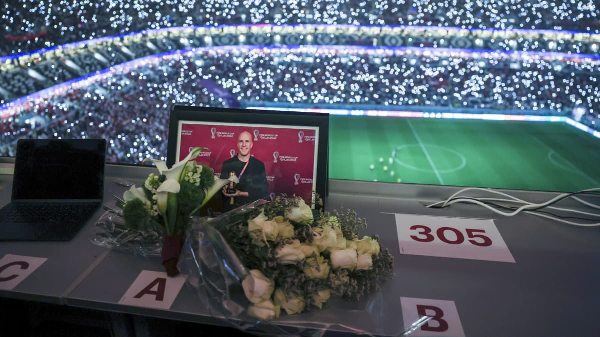 En blombukett framför ett porträtt på Grant Wahl på den plats där han satt på stadion.