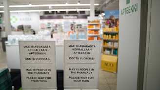 Henkilömäärän rajoituskyltit apteekin ovella koronapandemian aikaan 2020.