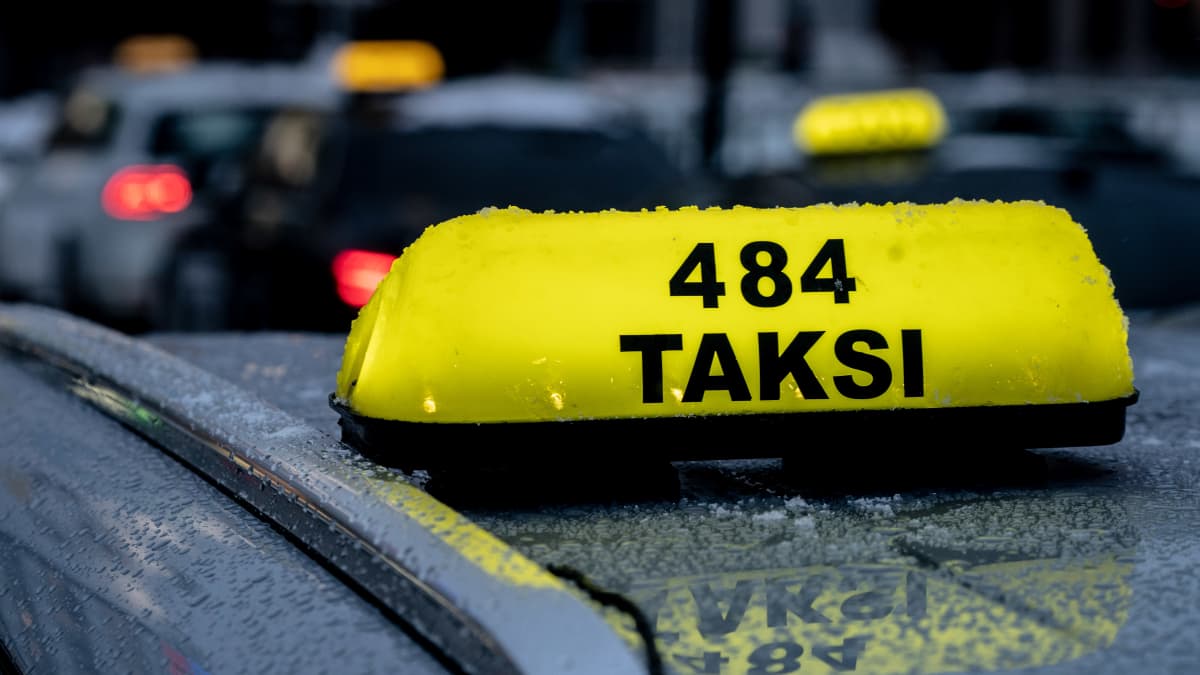 Taksikyltti auton katolla, taustalla muita takseja.