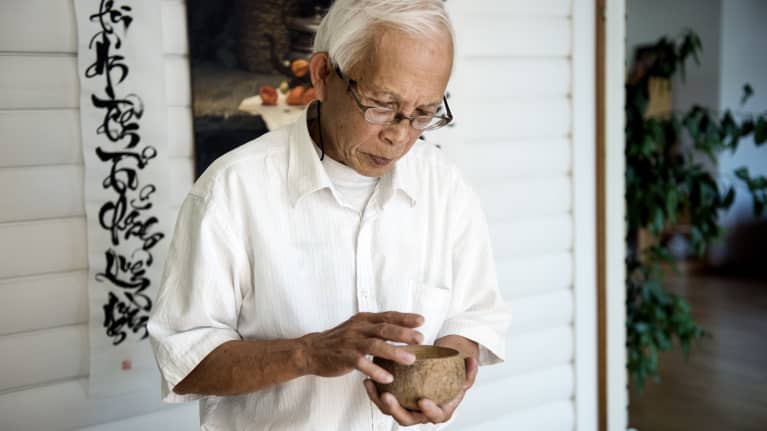 Tran Minh Canh silittää käsissään kookospähkinän puolikasta. Sileäksi hiottu kulho oli lautanen saarella, jonne perhe haaksirikkoutui 40 vuotta sitten, ennen saapumista Suomeen.