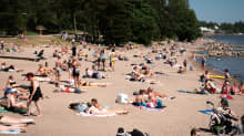 Ihmisiä ottamassa aurionkoa Mustikkamaan uimarannalla.