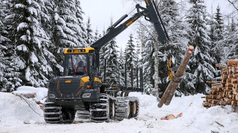 En så kallad skotare, en bandmaskin för skogsbruket, tar ut virke ur en snöig skog.