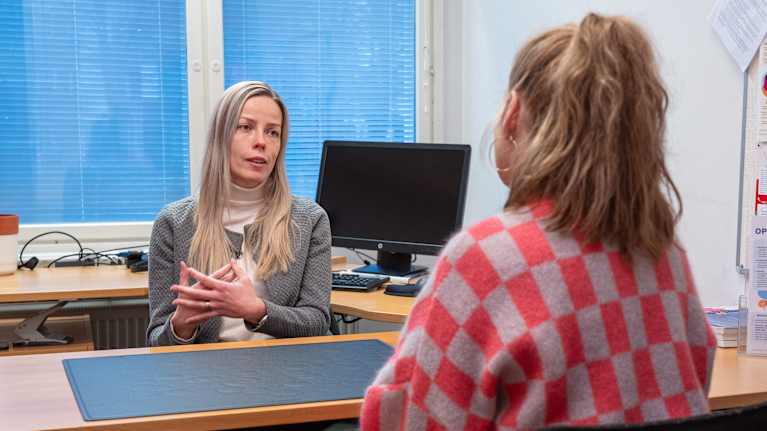 Johanna Stenberg istuu kirjoituspöydän ääressä ja keskustelee Tuulianna Tolan kanssa.