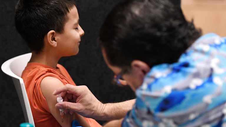 Pojalle laitetaan rokotusta käsivarteen.