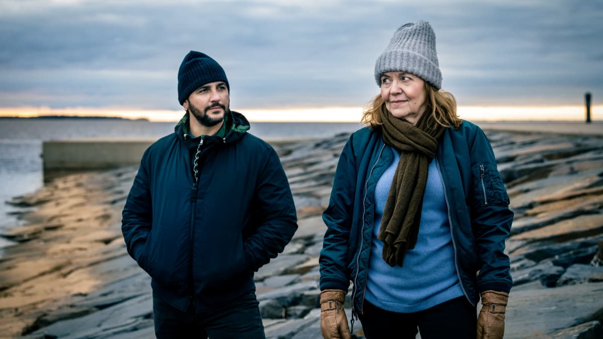 Paratiisi-sarjan Hilkka Mäntymäki ja Andrés Villanueva seisovat kallioisella rannalla.