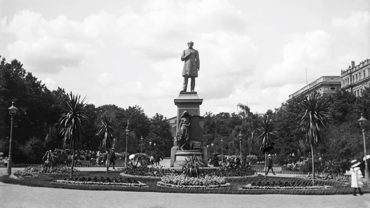 Vanhassa valokuvassa näkyy Runebergin patsas Espan puistossa palmujen ympäröimänä.