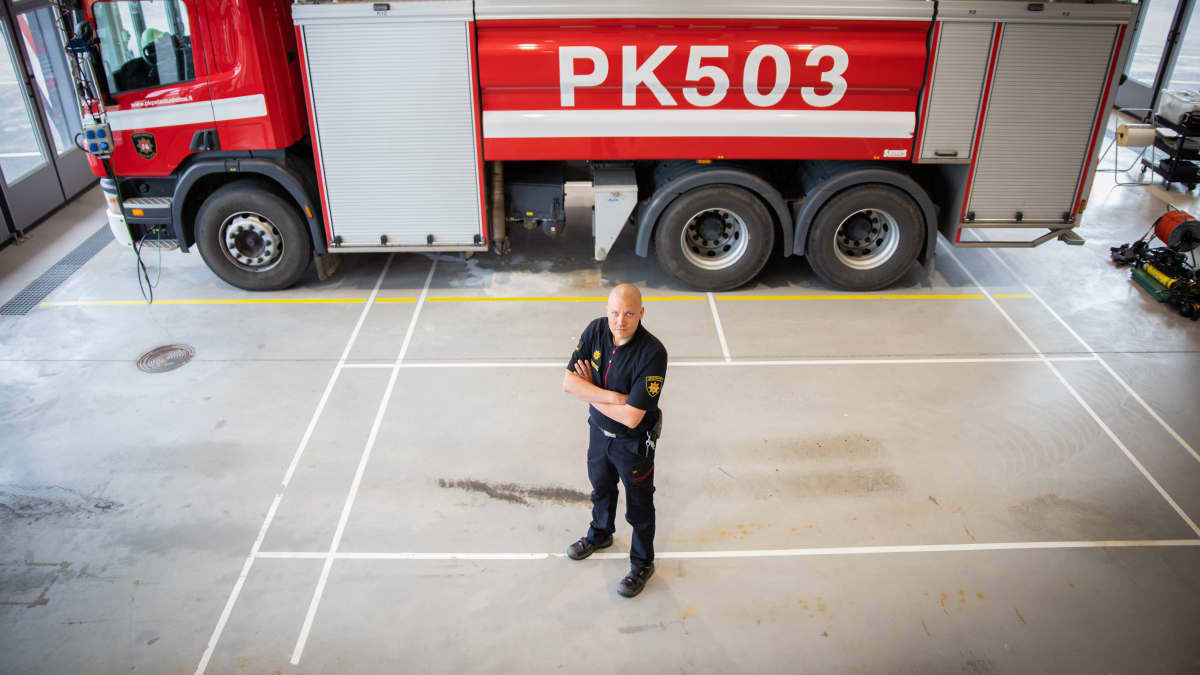 Ville-Petteri Pulkkinen seisoo hallissa paloauton vieressä.