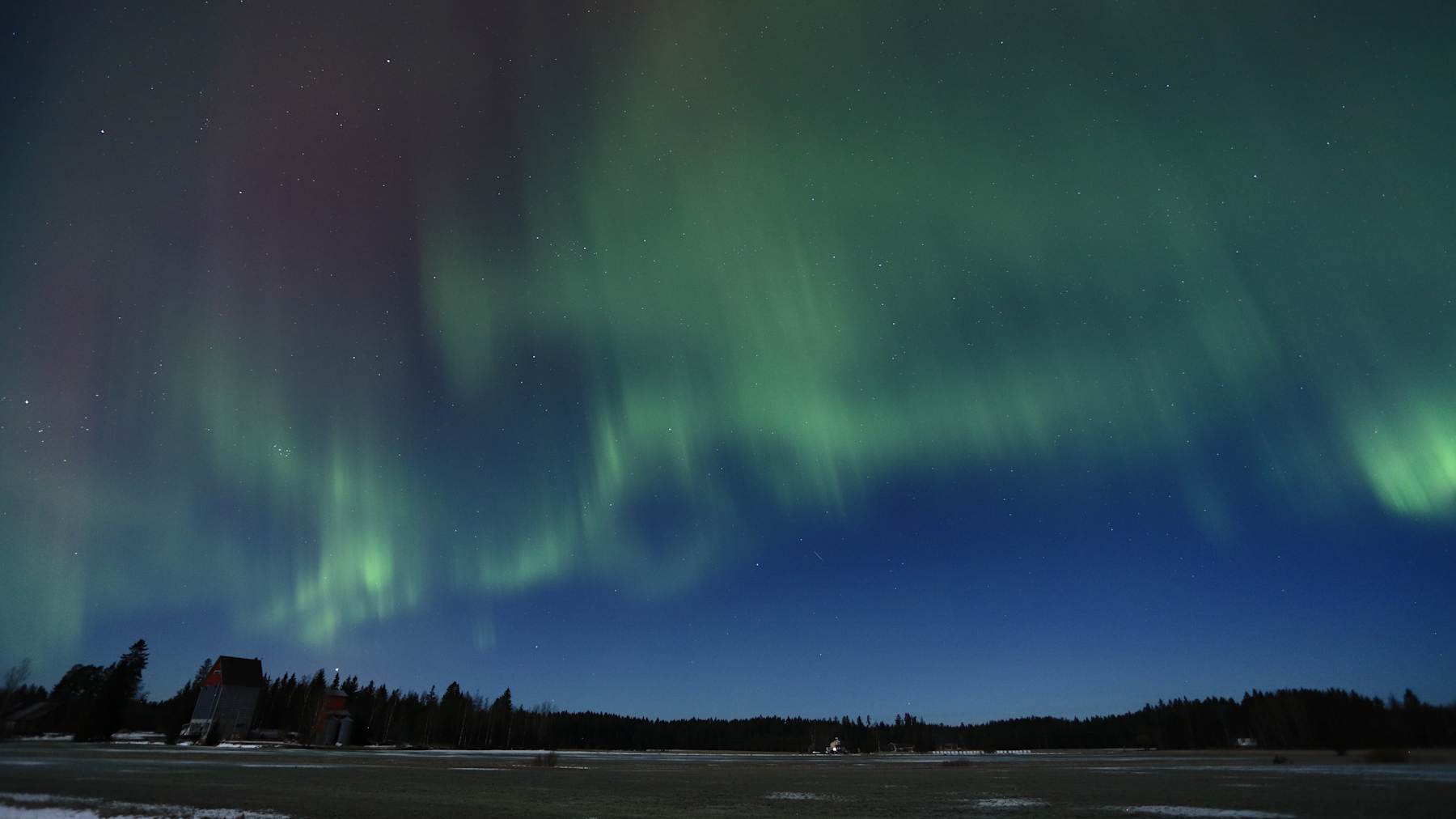 Peltomaisema, taivaalla revontulia.