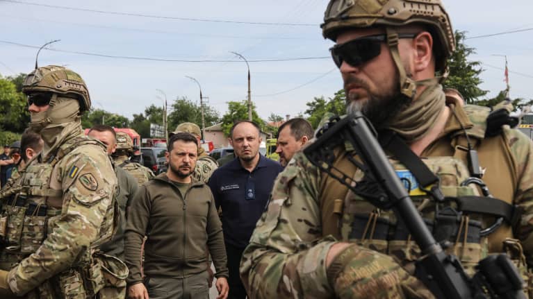 Zelenskyi seisoo sotilaiden ja viranomaisten keskellä.