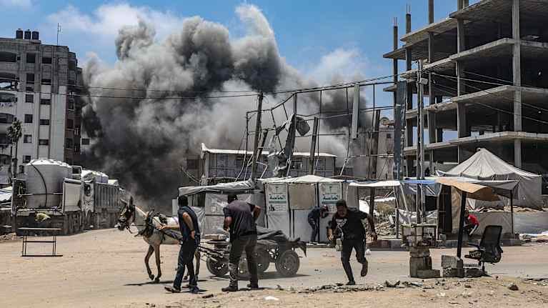 Gaza men run for cover from an Israeli airstrike.