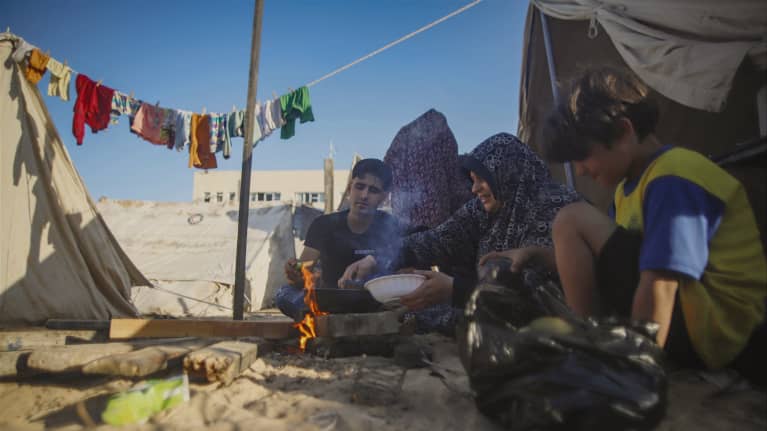 Palestiinalaisia pakolaisia Khan Younisin pakolaisleirillä nuotion ääressä aloittamassa ruokailua.