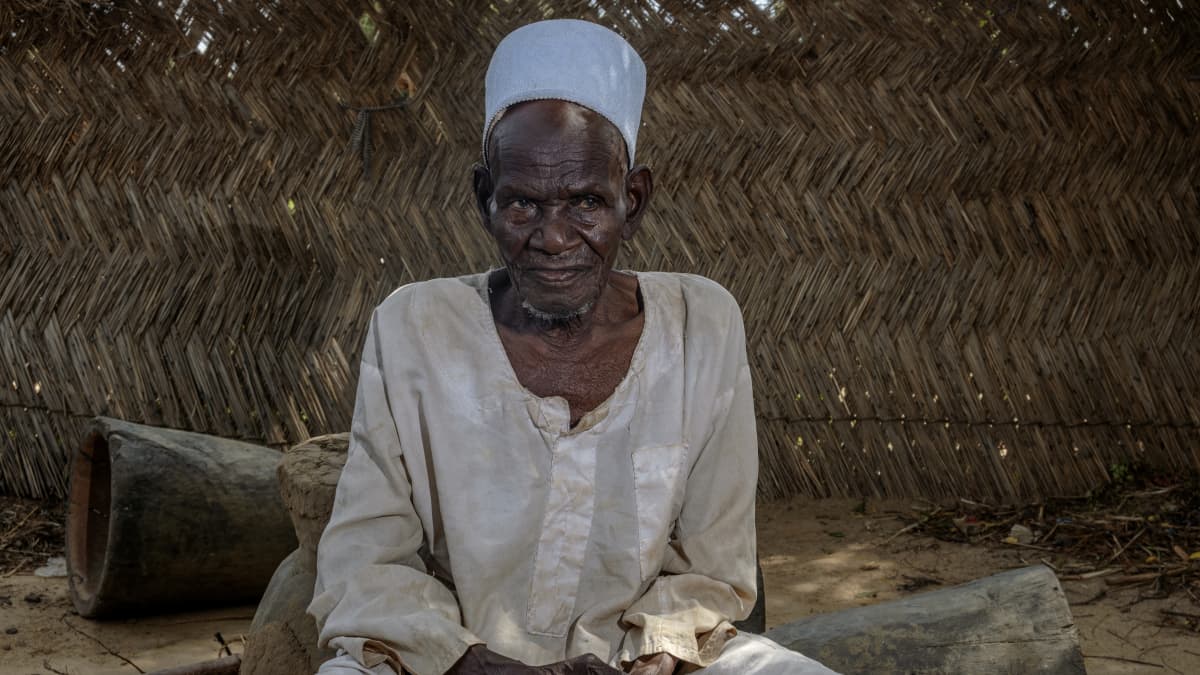 Vanha mies istuu nigeriläiskylässä.