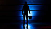Photo shows a person standing with a bucket in their hand.