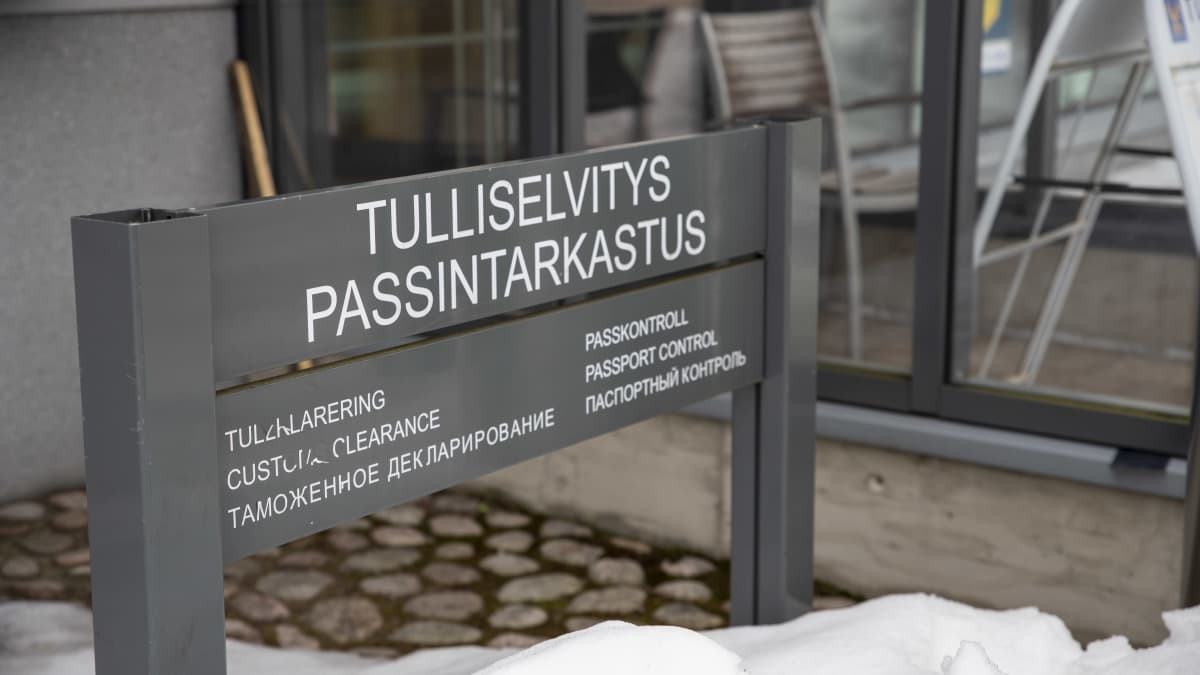 raja-aseman ovella oleva kyltti, jossa lukee "tulliselvitys" ja "passintarkastus" suomeksi ja muilla kielillä.