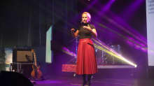 Punaiseen hameeseen ja mustaan t-paitaan pukeutunut Camilla Tuominen luennoi lavalla spottivalojen loisteessa.