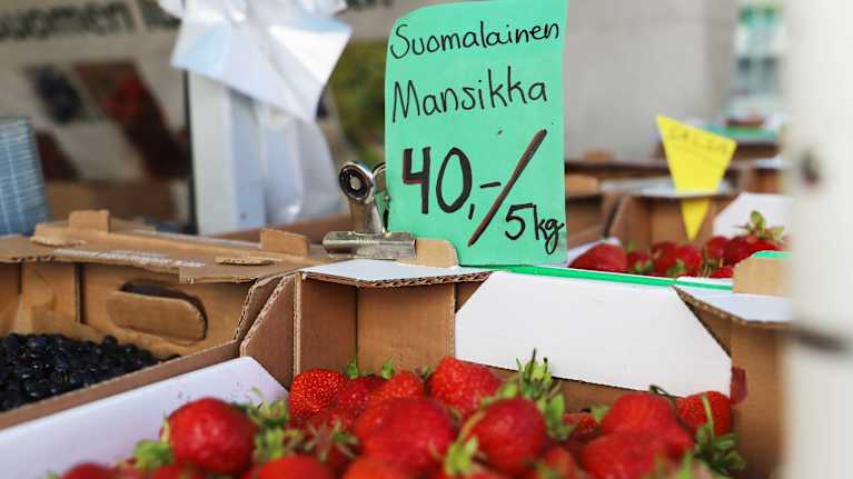 En papplåda med inhemska jordgubbar. En skylt med kilopris på en låda jordgubbar. 