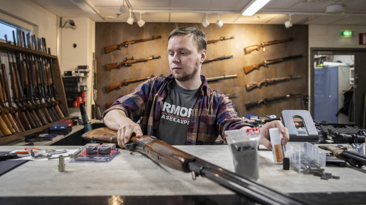 Armoria ase-liikkeen yrittäjä Veli-Matti Iskanius käsittelee haulikkoa liikkeen pöydällä.