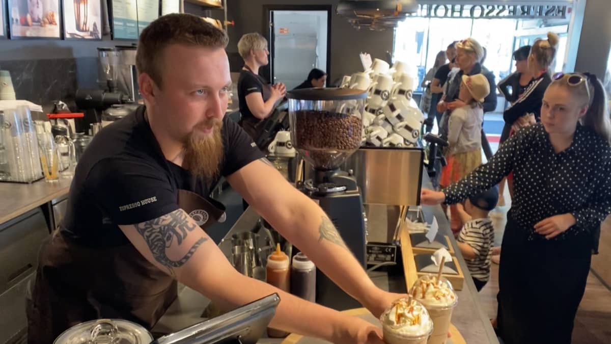 Kokkolan Espresso Housen työntekijä ojentaa kaksi take away -kahvia tiskille.