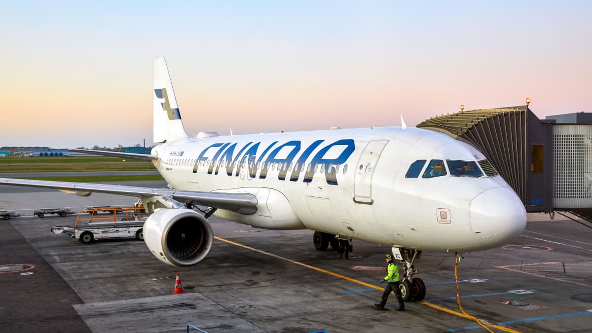 Ett Finnairflygplan parkerat på marken. I bakgrunden syns soluppgång.