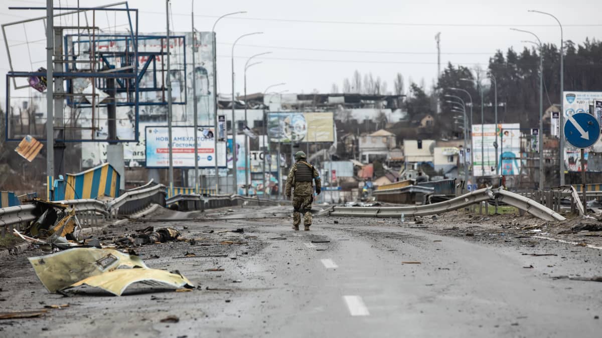 Ukrainalainen sotilas kävelee kadulla tuhojen keskellä.