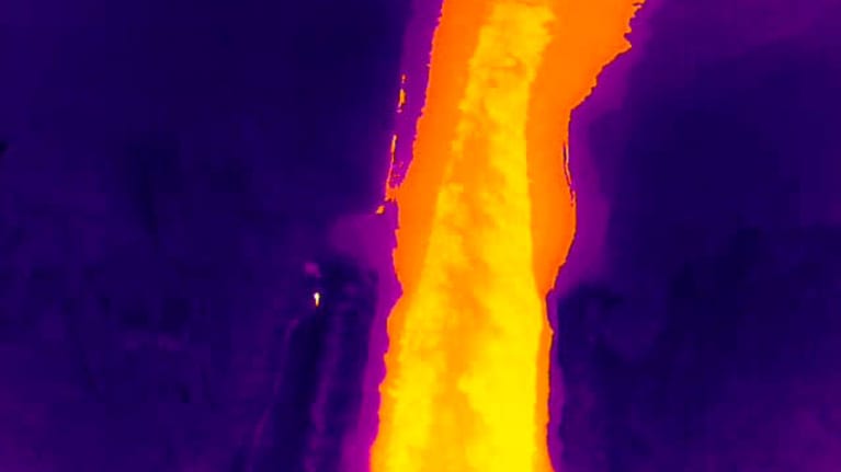 Lämpökamerakuvaa, joka hehkuu isolta osin violettina vesistön jään vuoksi. Keskellä sula alue, joka hohtaa keltaisena ja oranssina. Rannalla seisoo ihminen, joka hänkin hohtaa keltaisena.