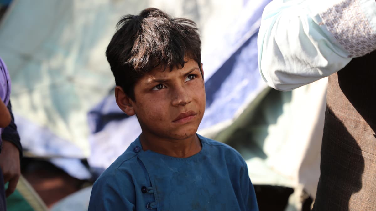 Poika katselee aikuisia pakolaisleirillä Kabulissa.