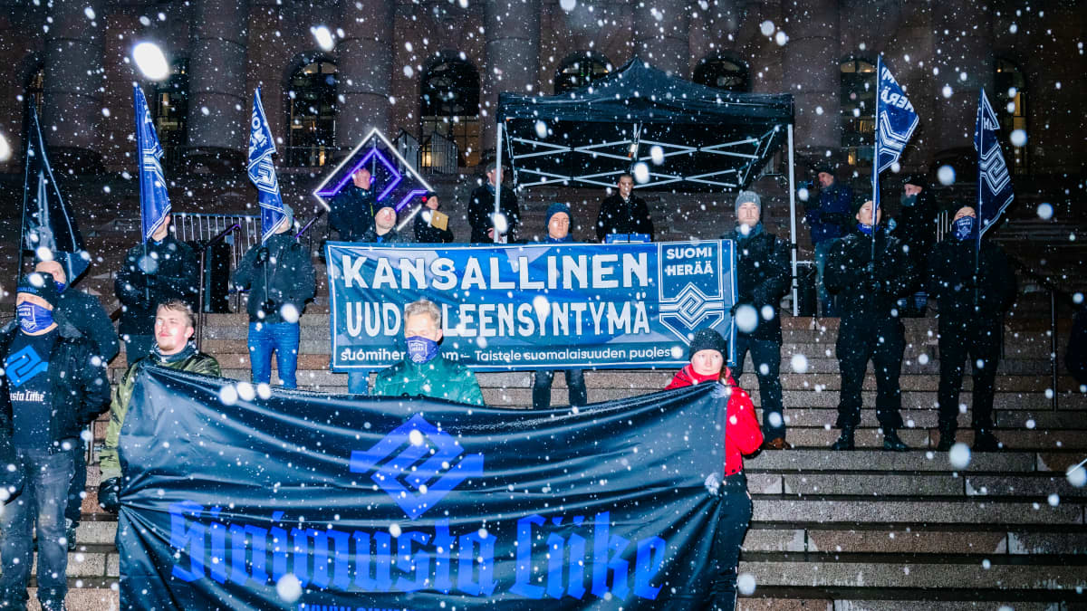 Äärioikeiston mielenosoittajia Suomen lippujen ja iskulauseiden kanssa eduskuntatalolla.
