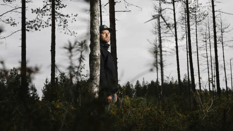 Suomen Ympäristökeskuksen erikoistutkija Santtu Karhinen seisoo metsässä tuulivoimapuiston laidalla.