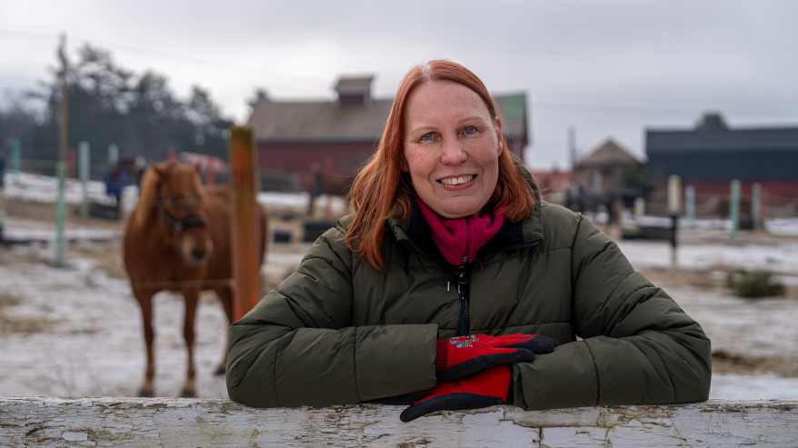 Eläinavusteinen toimintaterapeutti Kirsi Pihlava nojailee hevosaitaukseen.