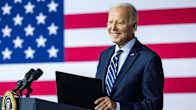 Joe Biden stands at a podium with the US flag in the background.