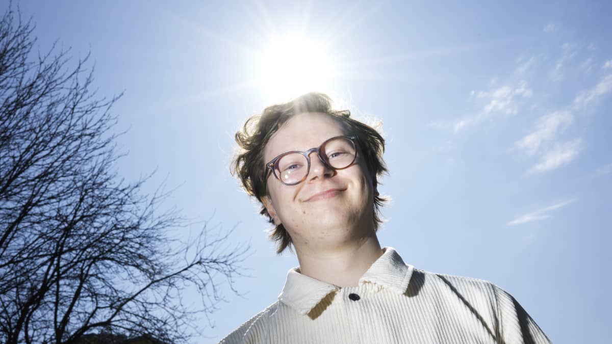 Hymyilevä mies katsoo kameraan ja aurinko paistaa selnatakana.