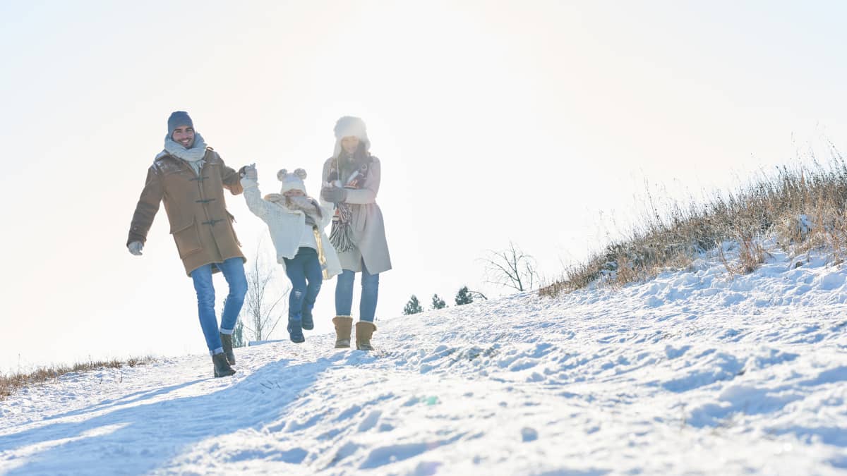 Mamma, pappa, barn i ett snöigt landskap. 