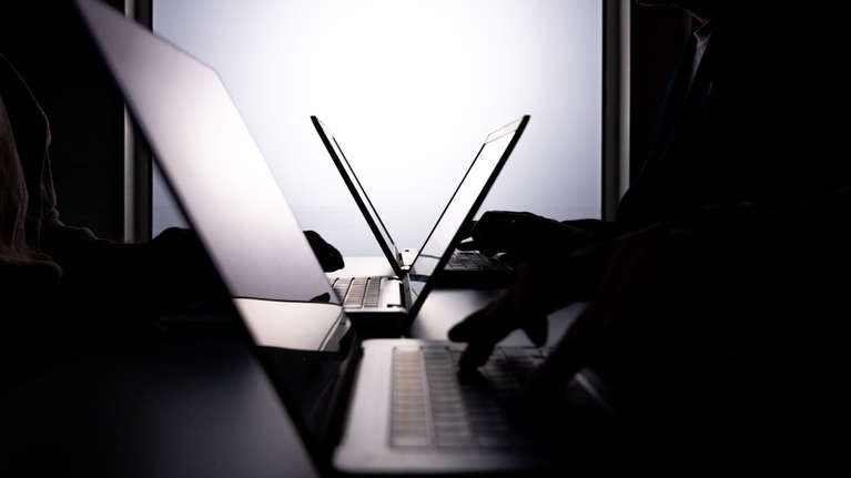 På bilden sitter två personer vid ett bord och arbetar med var sin laptop. 