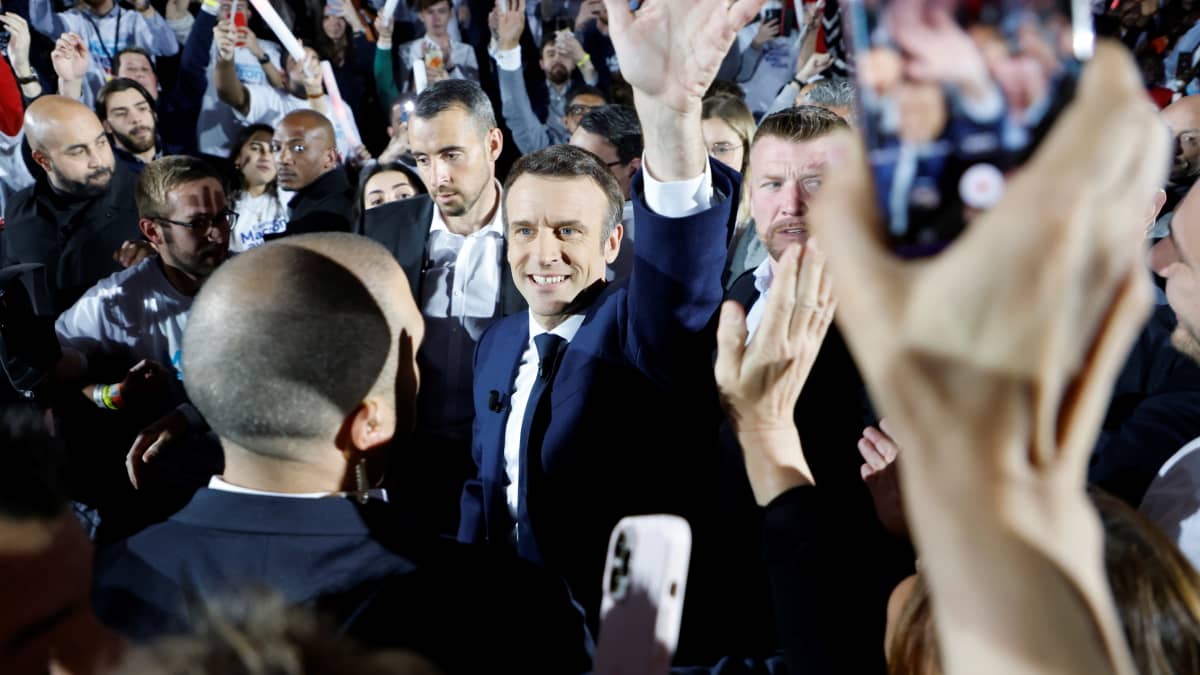 Emmanuel Macron vilkuttaa kampanjatilaisuudessa ihmisten ympäröimänä.