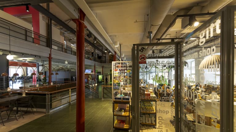 Tampereen Tampellan sisätiloja vuonna 2022. Kuvassa näkyy pientä myymälää, myyntitiskiä ja kahviota.