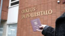 Passi kädessä Kajaanin oikeus- ja poliisitalon edustalla