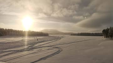 Aurinko pilkahti Kätkätunturilla. Latuja järven jäällä. 