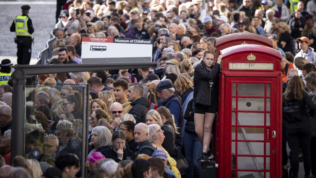 Tusentals personer samlades i Edinburg för att följa med processionen. En flicka har klivit upp på en telefonkiosk.