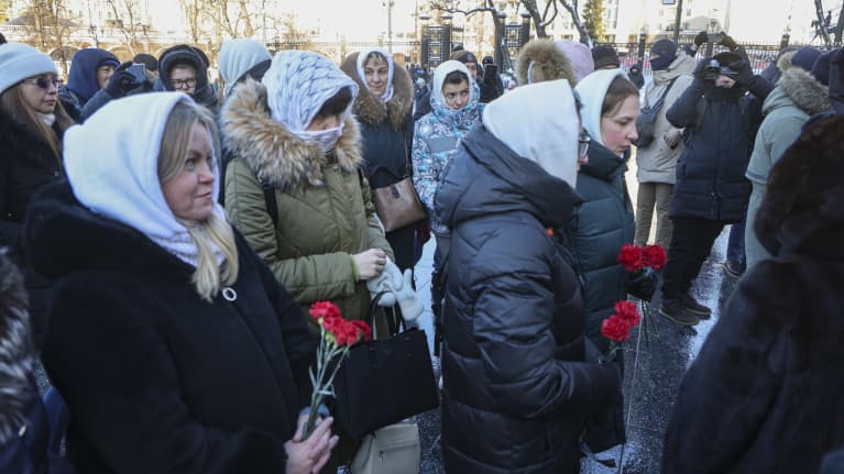 Joukko naisia kantaa käsissään ruusuja. Monilla heistä on päässään valkoinen huivi.